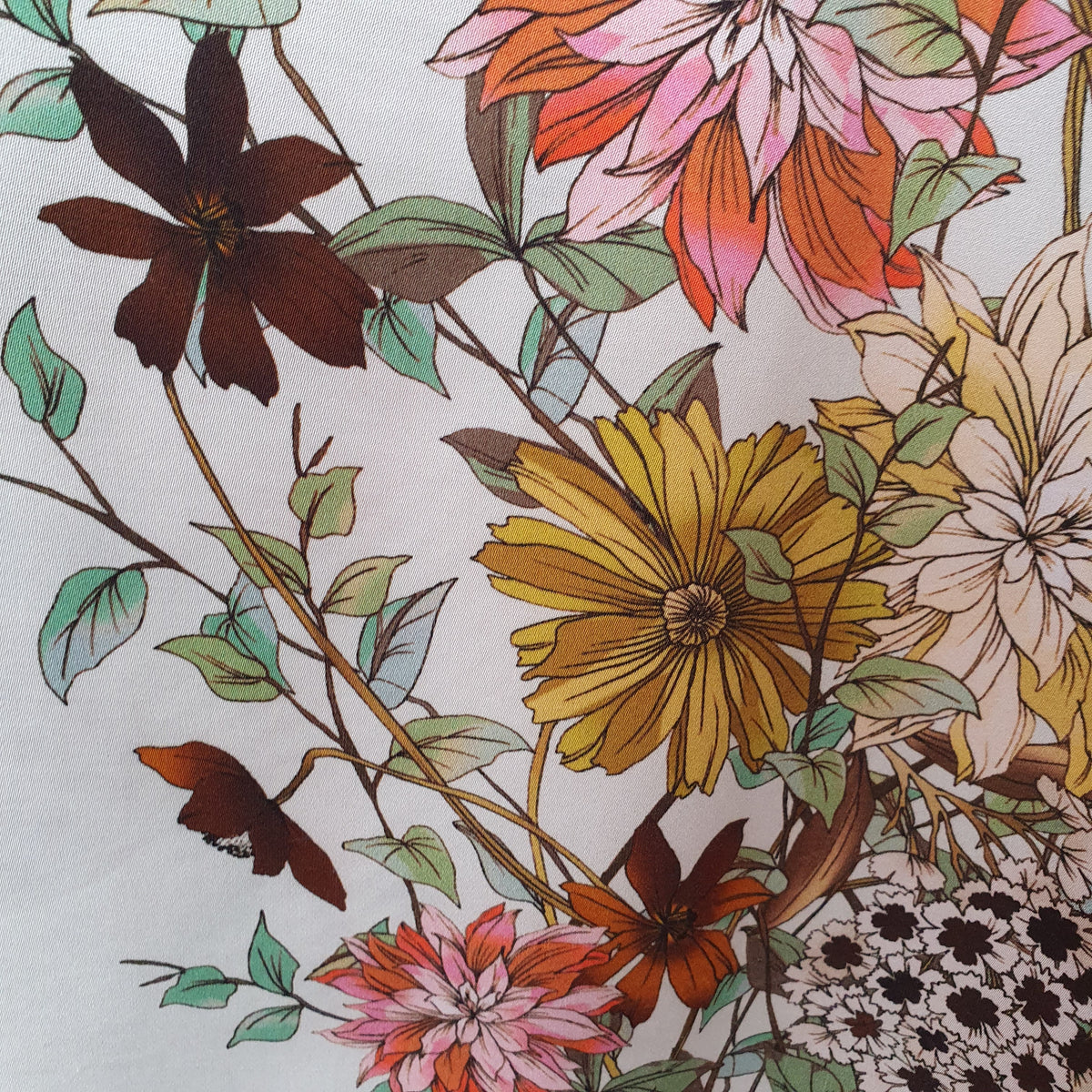 Gros plan sur les fleurs jaunes, roses et brunes du chemisier Madeleine