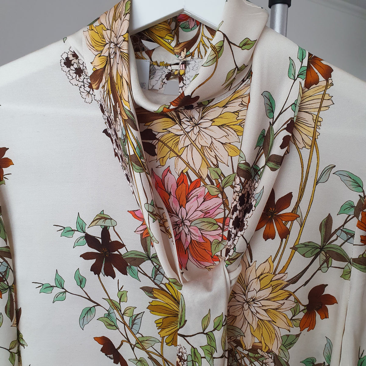 Détail de la lavallière du chemisier Madeleine et de ses fleurs roses, jaunes et orangées
