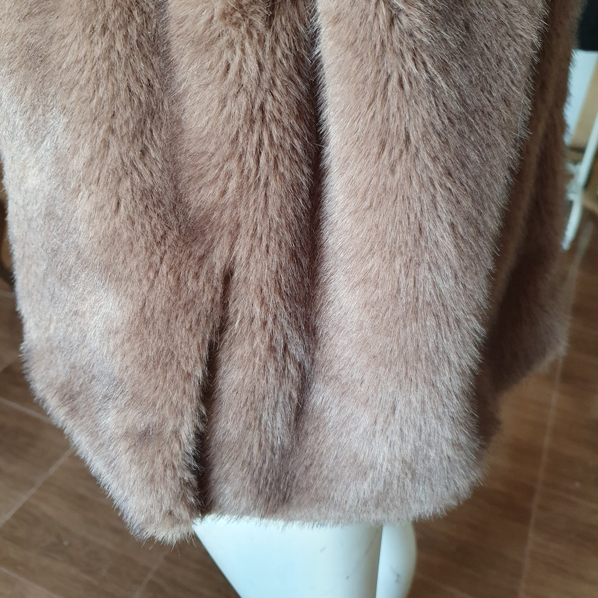 Détail d’une fente latérale à la base de la tunique en fausse fourrure taupe