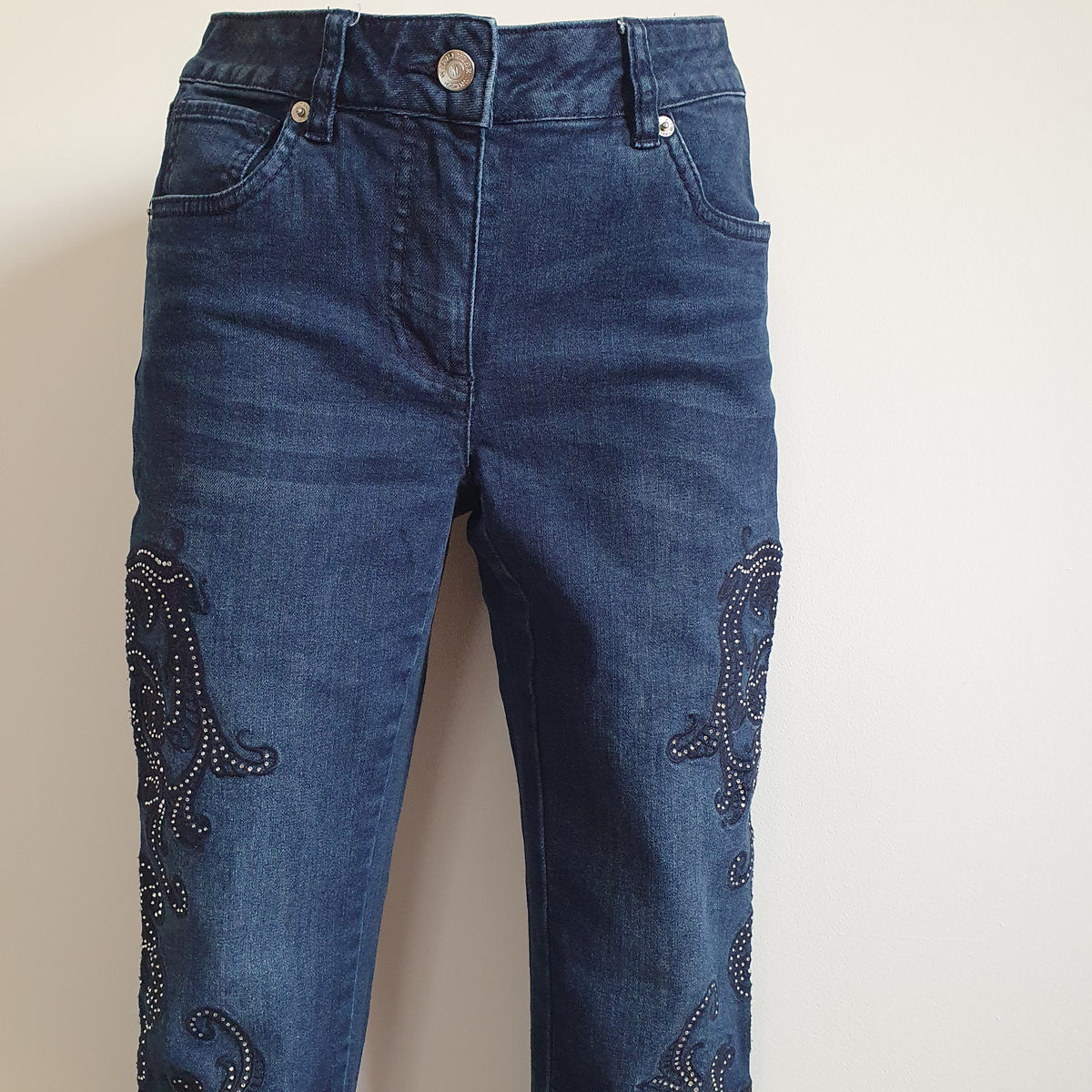 Taille du jean bleu Madeleine avec bouton, passants, poches avant et poche ticket, au-dessus des motifs à strass.