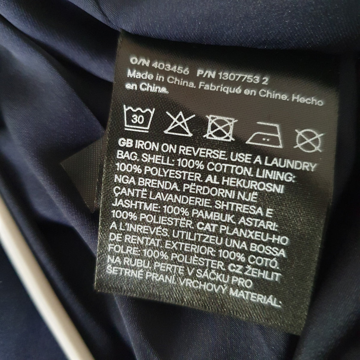 Étiquette de la veste : extérieur 100 % coton, doublure 100 % polyester et consignes d’entretien 