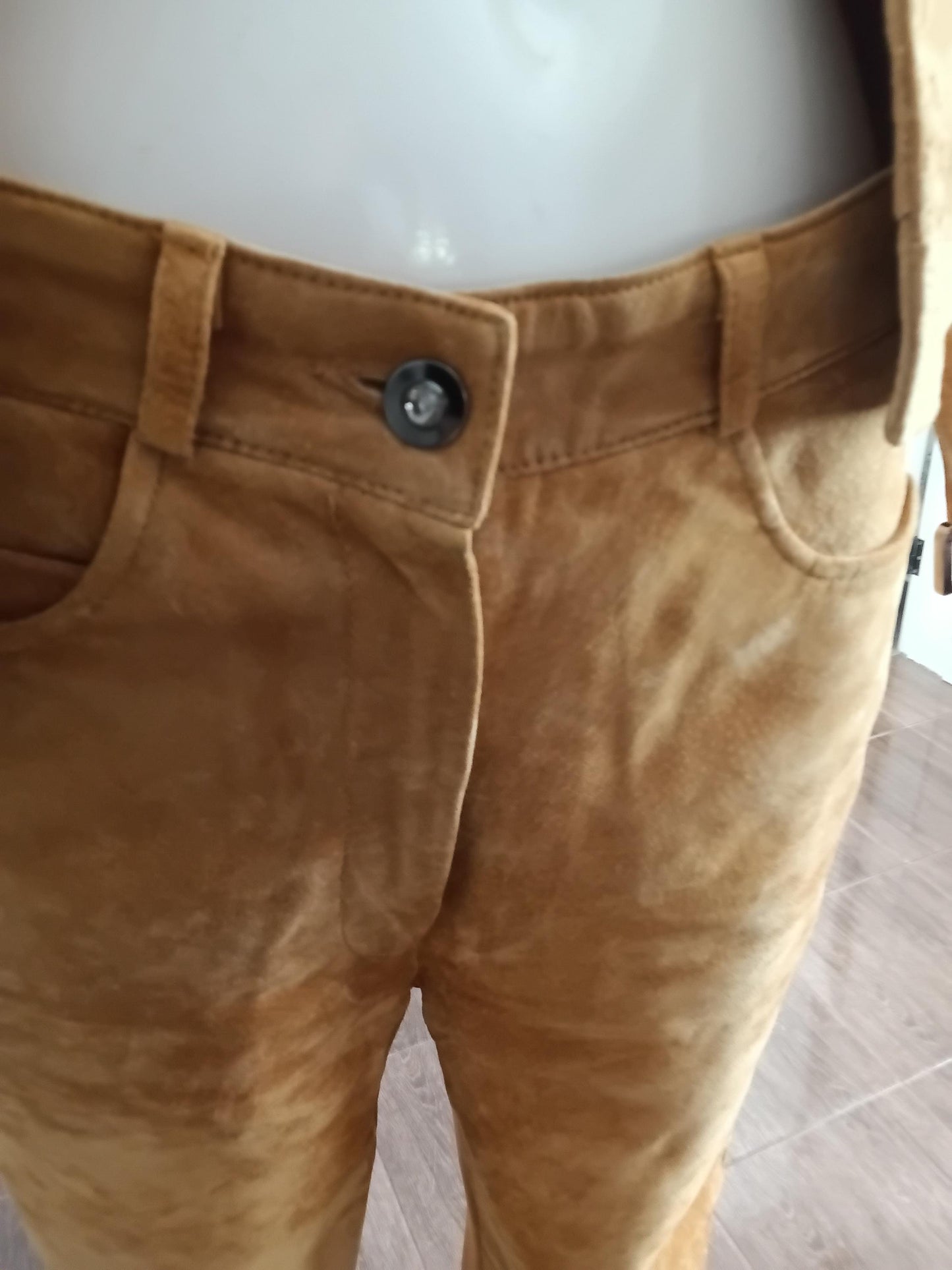 Détail ceinture intégrée et bouton du pantalon tailleur daim moutarde — fermeture taille haute, texture cuir suédé véritable