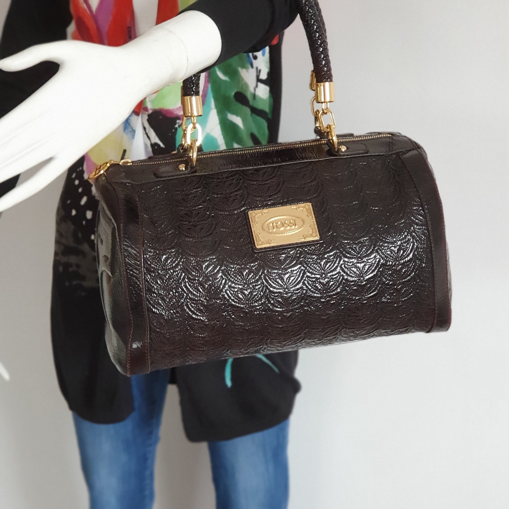 Gros plan sac bowling Silvio Tossi cuir embossé chocolat porté au coude