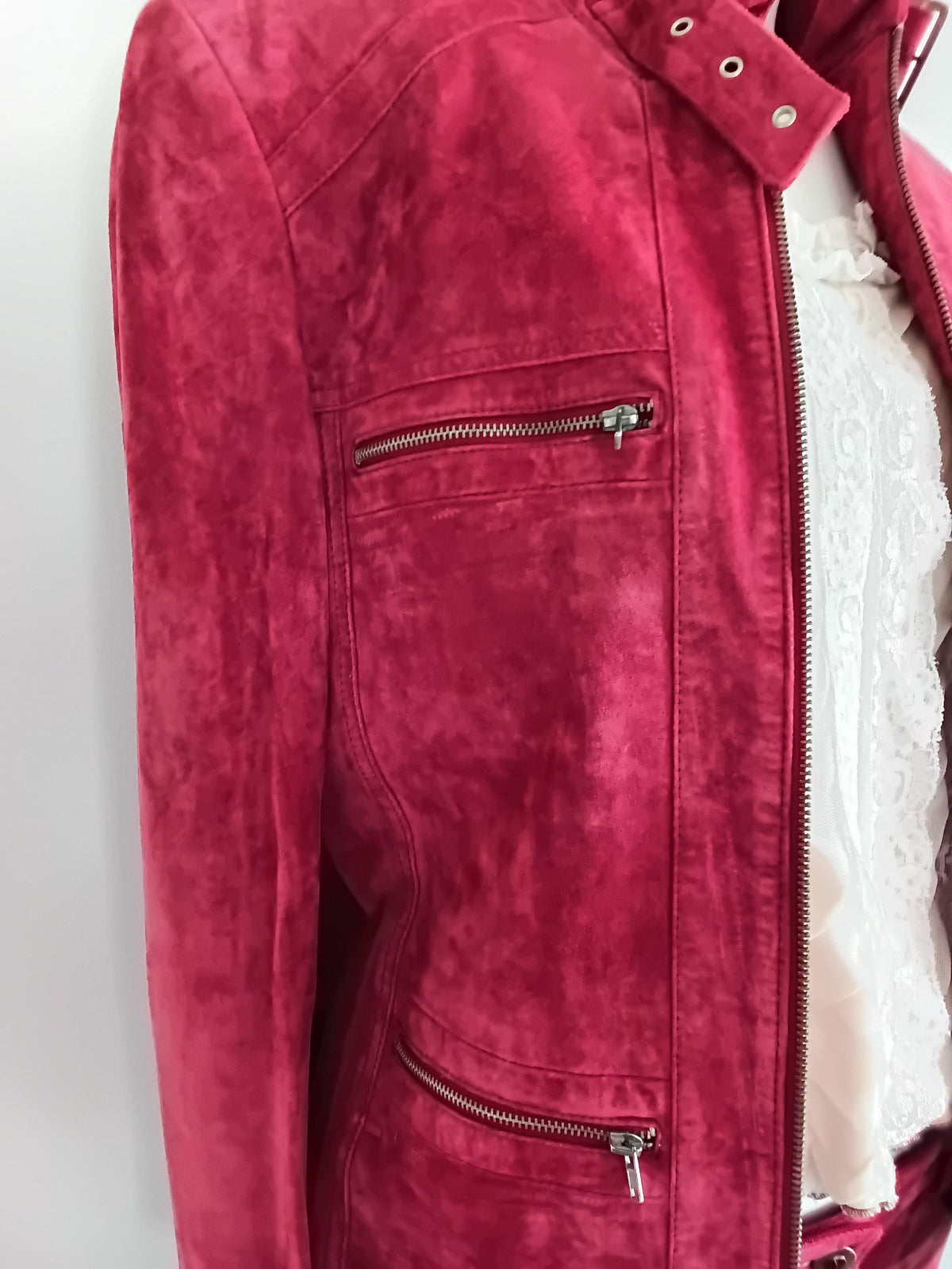 Gros plan poches zippées veste cuir framboise — détail fermeture éclair argentée