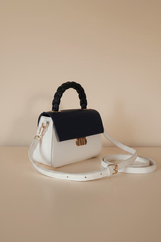 Sac à main bicolore blanc bleu marine — vue de face légèrement de profil, anse tressée noire et clip doré Art Déco, style rétro chic